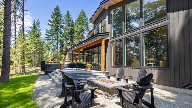 Una casa moderna con patio que incluye una chimenea de piedra y mobiliario exterior.