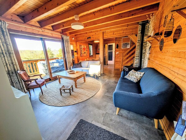Interior acogedor de una cabaña de madera con sofá, mesa de centro y mesa de comedor.