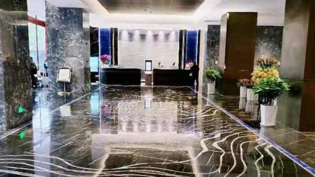 Un vestíbulo amplio con piso de mármol pulido, una recepción y plantas en macetas.