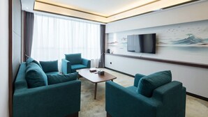 Una sala de estar moderna con sofás turquesa, una mesa de centro de madera y un televisor de pantalla plana grande montado en la pared.