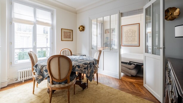 A dining room with a table set for four, a radiator, and a window with blinds. - Honeybee Soul, by Veeve (Paris)