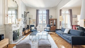 A spacious living room with a fireplace, a sofa set, a coffee table, and a large mirror. - Clichy Couture, by Veeve (Paris)