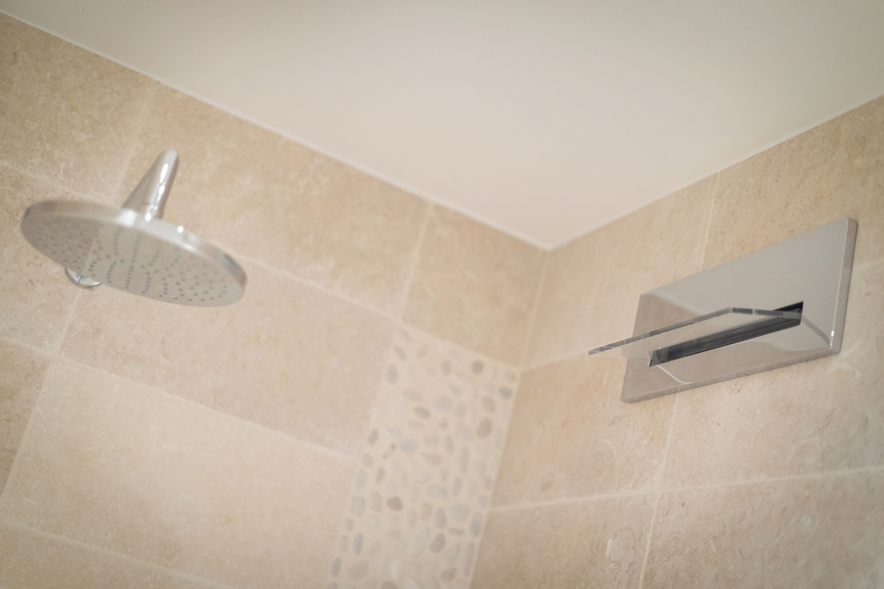 A shower with a handheld showerhead and a wall-mounted control panel.