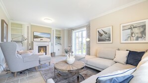 Un salon avec une cheminée, un canapé, un fauteuil et une table basse.