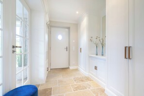 Un couloir avec une porte blanche, un banc bleu et un sol carrelé.
