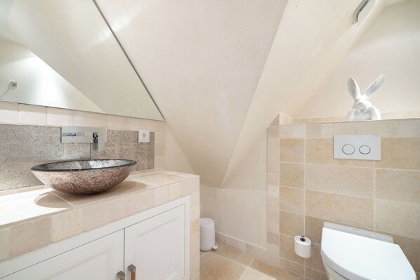 A modern bathroom with a large vessel sink, white cabinetry, a toilet, and a towel rack. - Wattblick. Reet. Sauna (Sylt)