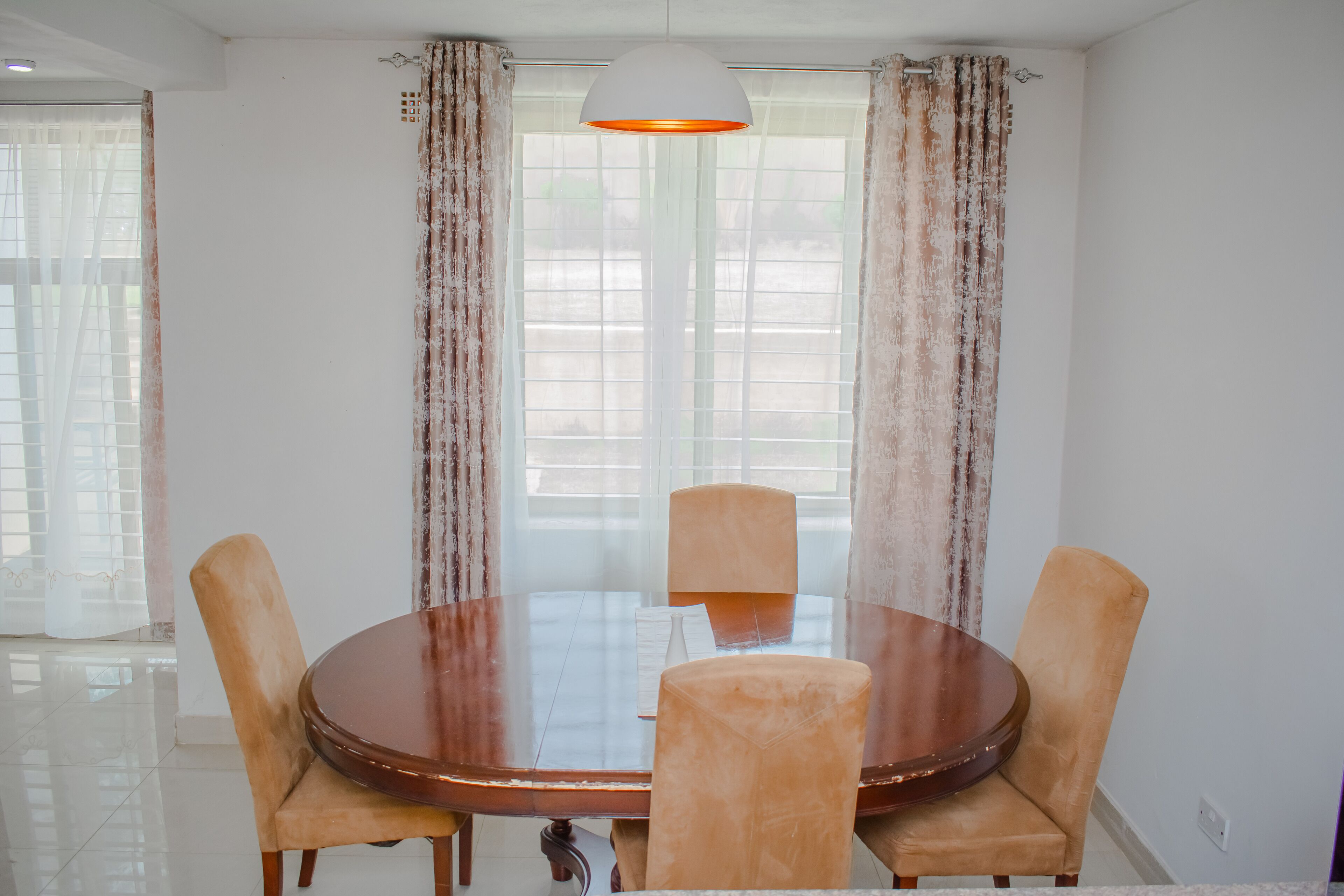 Uma sala de jantar com uma mesa redonda, quatro cadeiras e um lustre.