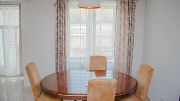Uma sala de jantar com uma mesa redonda, quatro cadeiras e um lustre.