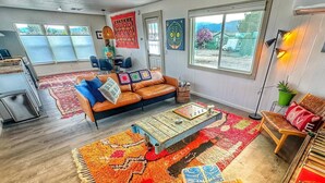 Un salon spacieux avec un grand canapé, une table basse et des tapis aux couleurs vives.