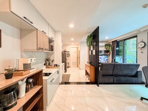 A modern kitchen with a dining area, a sofa, and a view of the outdoors.
