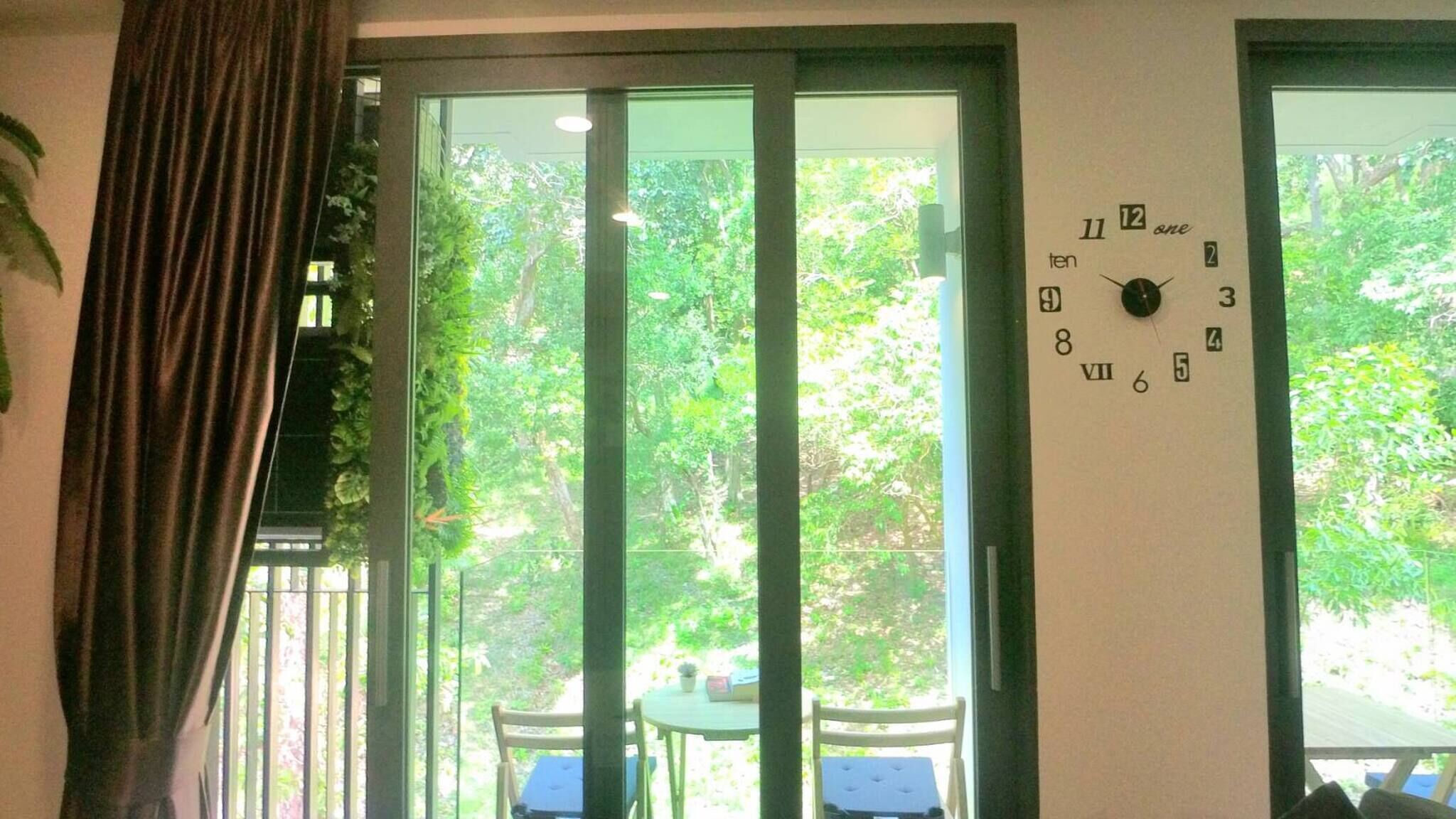 Une pièce avec une grande fenêtre, une horloge au mur et un rideau.