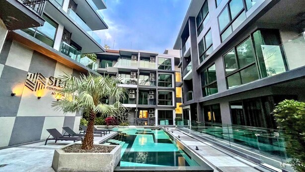 A modern building with a swimming pool, lounge chairs, and a sign for 'STELLA CONDOMINIUM.' - A206- 2 Bedroom Serviced Apartment with Forest View at Ao Nang Beach (Tambon Ao Nang)