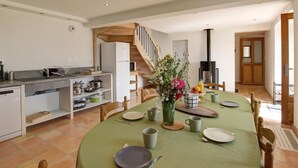 A spacious kitchen with modern appliances, a dining area with a green table set for four, and a staircase leading to another level. - Renovated traditional farmhouse with private courtyard in Verrières-en-Forez (Verrières-en-Forez)