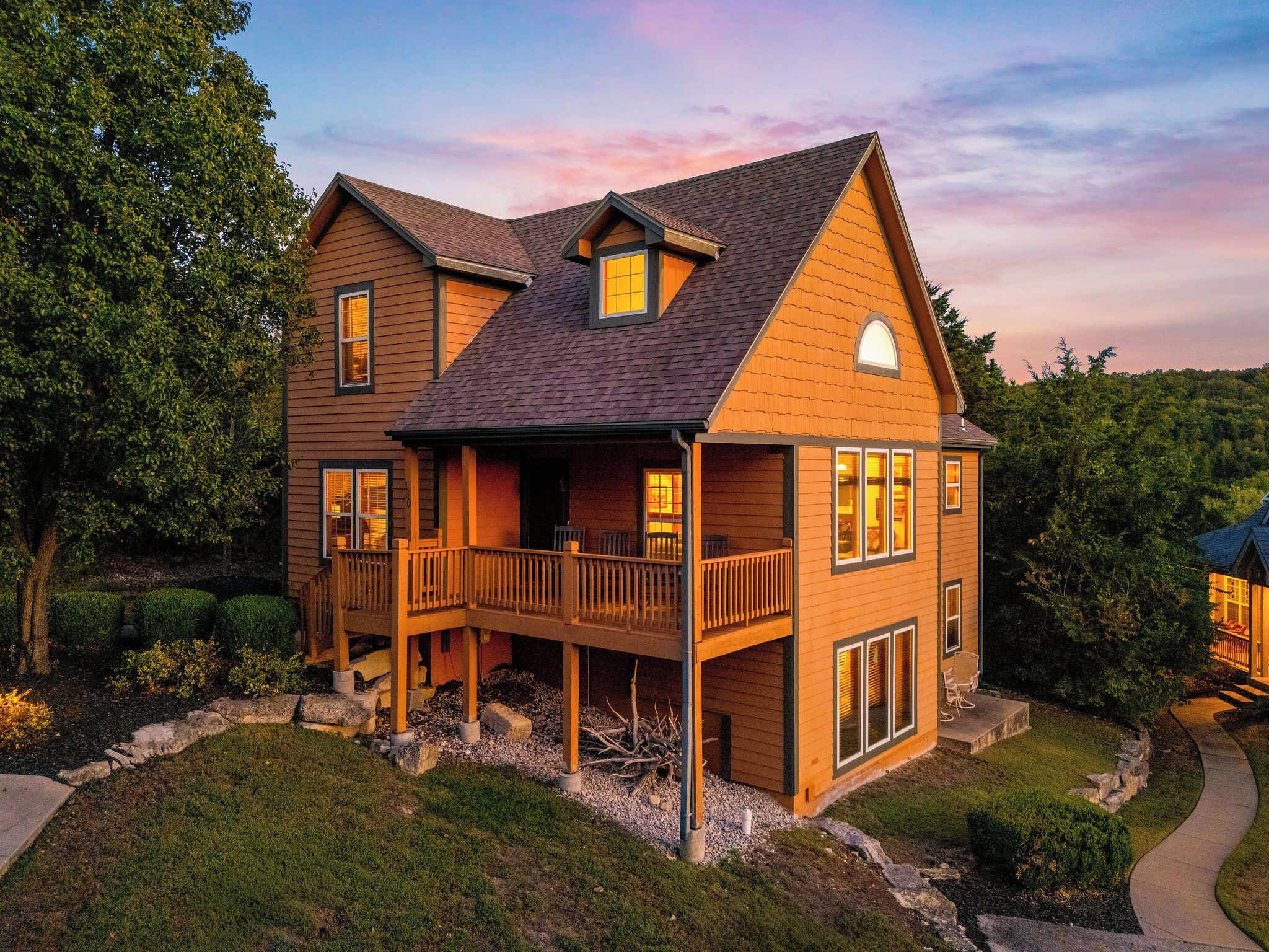 A two-story wooden house with a balcony, a front porch, and a driveway.