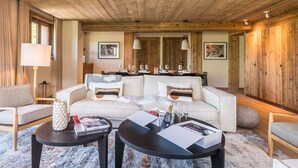 Ein gemütliches Wohnzimmer mit Holzbalkendecke, einer Chandelüstere, einem Sofa und einem Essbereich.