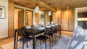 Ein Essbereich mit Holzbalkendecke, gedecktem Tisch mit Tellern und Gläsern sowie einer Couch mit Decke.
