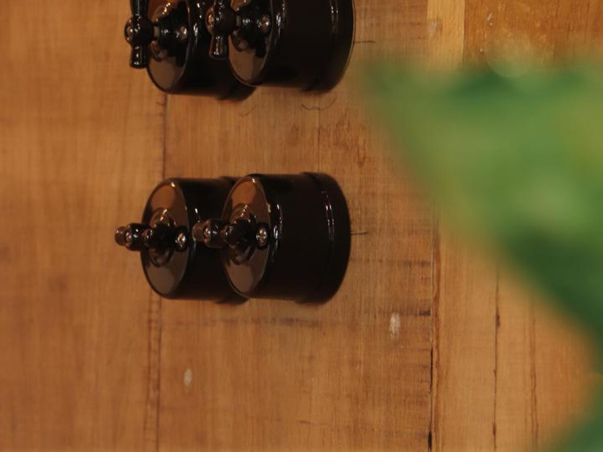 Deux objets cylindriques noirs reposent sur une surface en bois.