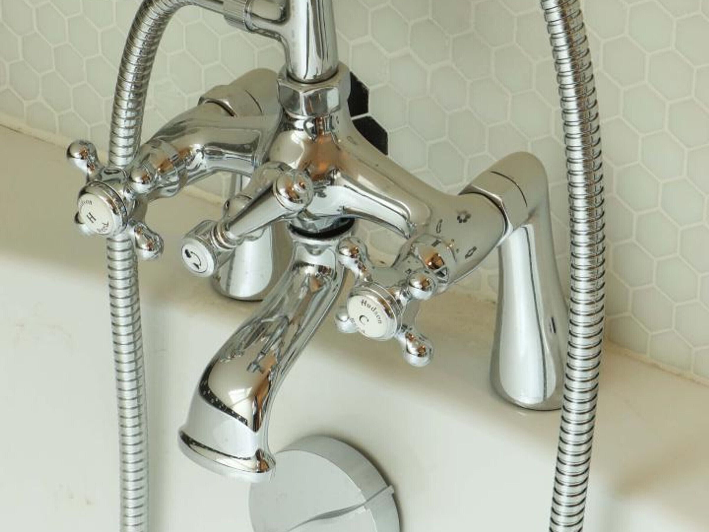 Un robinet de salle de bain chromé doté de plusieurs têtes de pulvérisation et de tuyaux flexibles.