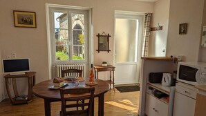 Een gezellige keuken met een eettafel, stoelen, een televisie en een magnetron.