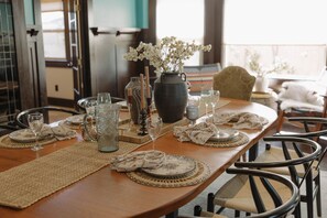 A dining table set with plates, glasses, and a vase of flowers.