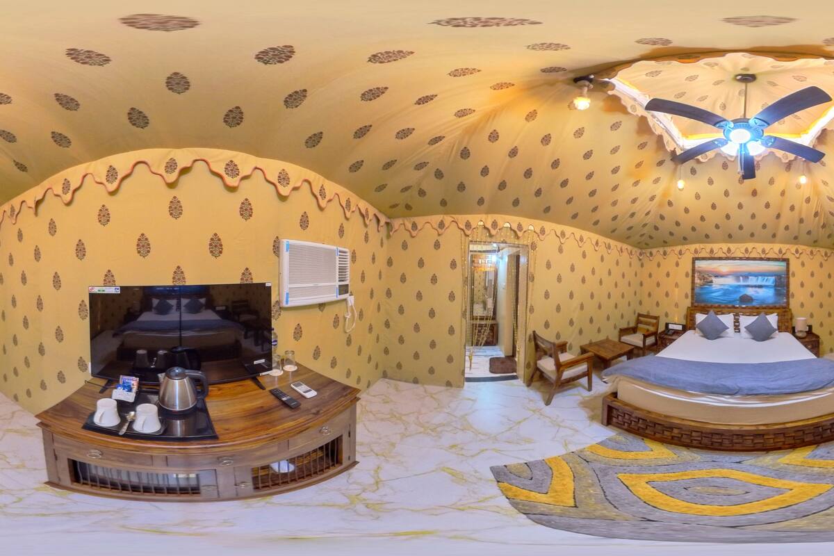 Ein geräumiger Raum mit einem großen Bett, einem Fernseher, einer Sitzecke mit Couchtisch und einer dekorativen Decke.