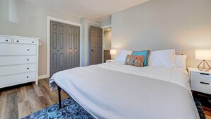 A bedroom with a large bed, a dresser, and two doors.