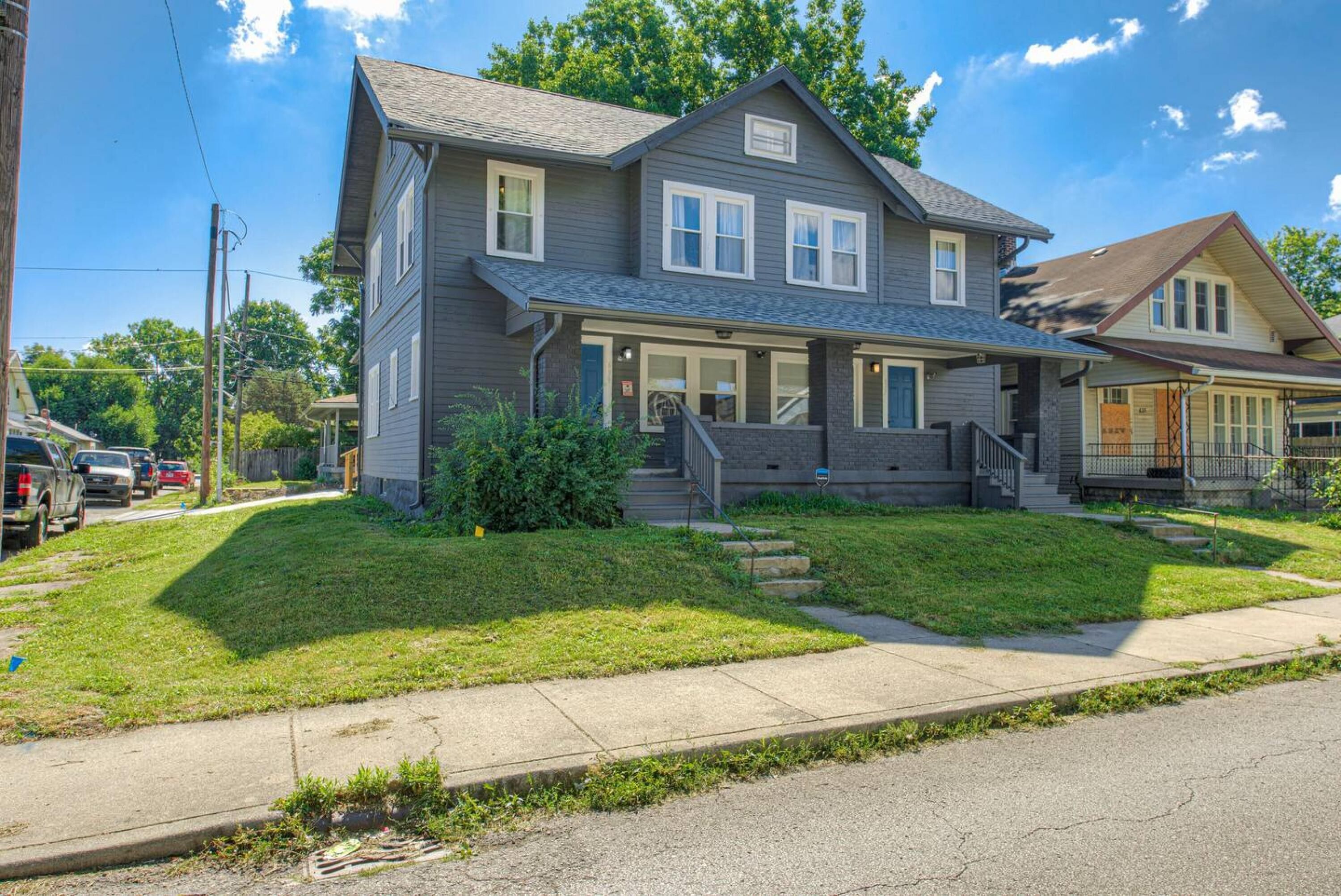 A two-story house with a front porch, a driveway, and a small front yard.