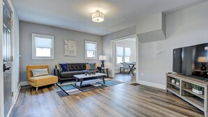 A spacious living room with hardwood flooring, a sofa, a coffee table, and a TV.