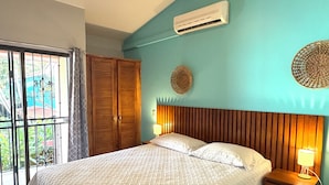 A bedroom with a bed, a ceiling fan, an air conditioner, and a view through a window. - Happy Oasis Second Floor Condo with Terrace (Playas Del Coco)