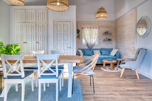 Een moderne woonkamer met houten vloer, witte meubels en een blauwe bank.