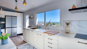 A modern kitchen with white cabinets, a large window, and a view of the sea. - EL SUEÑO : Fantastic house in Pals with private pool and wonderful views of the Medes Islands (Pals)