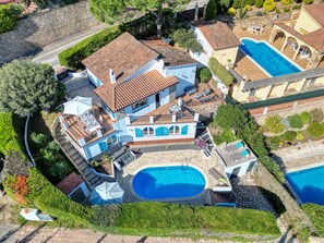 An aerial view of a residential property with a swimming pool, a patio area, and a stone wall. - EL SUEÑO : Fantastic house in Pals with private pool and wonderful views of the Medes Islands (Pals)