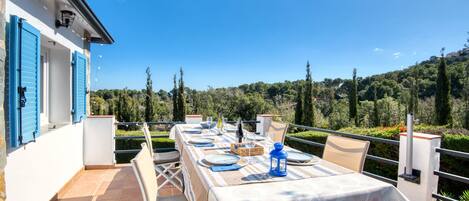 Un área de comedor al aire libre con una mesa preparada para cuatro, con vistas a un paisaje pintoresco.