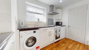 Une cuisine compacte équipée d’un lave-linge, d’un four à micro-ondes et d’une cuisinière.