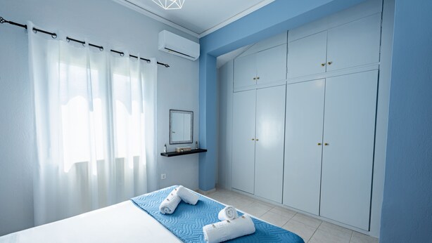 A bedroom with a bed, a wardrobe, a mirror, and a shelf. - La Casa di Volpe (Corfu)