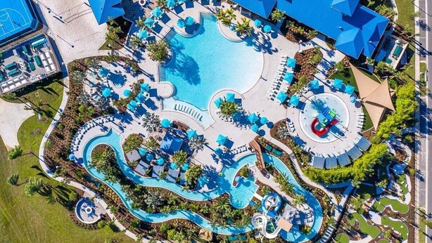 An aerial view of a resort with a central swimming pool, multiple water slides, and sun loungers.