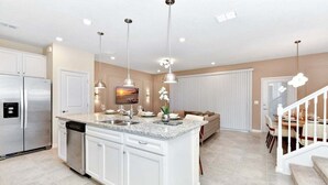 A modern kitchen with white cabinetry, a granite countertop, and stainless steel appliances.