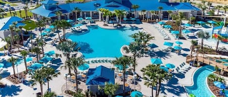 A resort with a large central pool, multiple smaller pools, and numerous sun loungers and umbrellas.