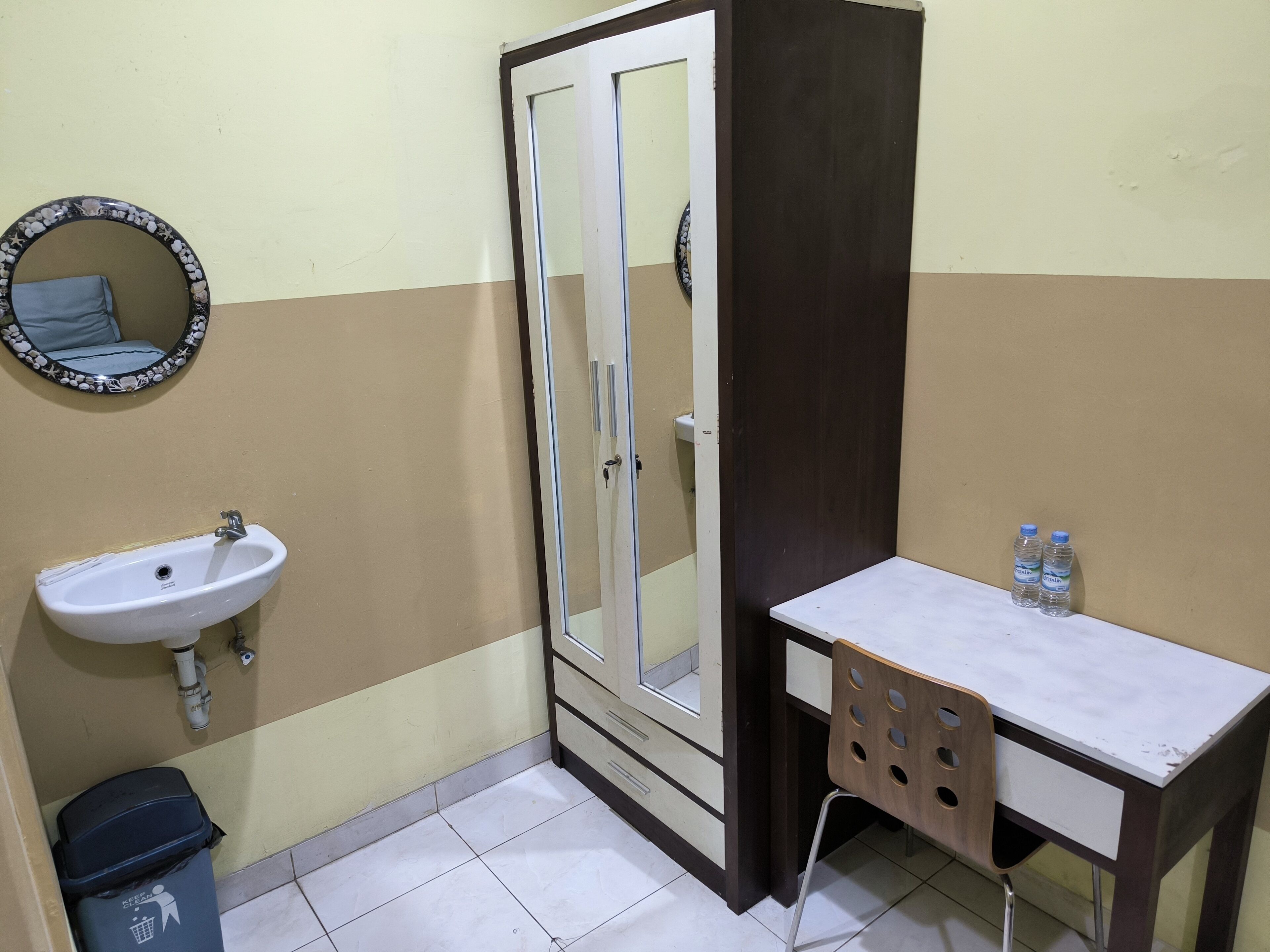A bathroom with a sink, mirror, shower, and a small table with water bottles.