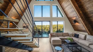 Un loft espacioso con interior de madera, un gran ventanal y una escalera moderna.