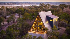 Una casa moderna con un amplio ventanal, rodeada de árboles y vista al océano.