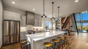 Una cocina moderna con una isla grande, electrodomésticos de acero inoxidable y taburetes de madera.
