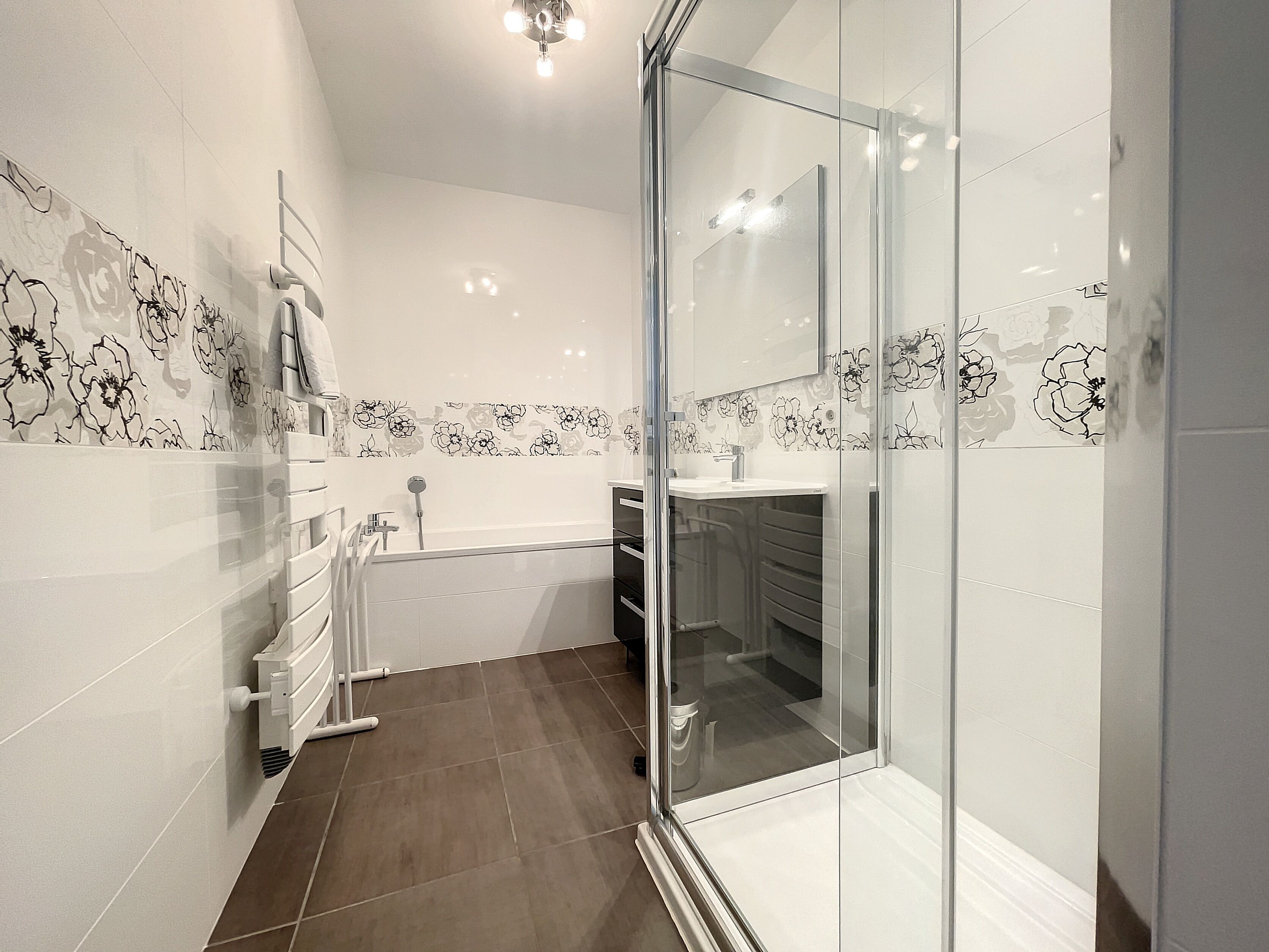 A modern bathroom with a glass shower enclosure, a bathtub, and a vanity with a sink.