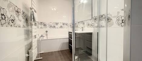 A modern bathroom with a glass shower enclosure, a bathtub, and a vanity with a sink.