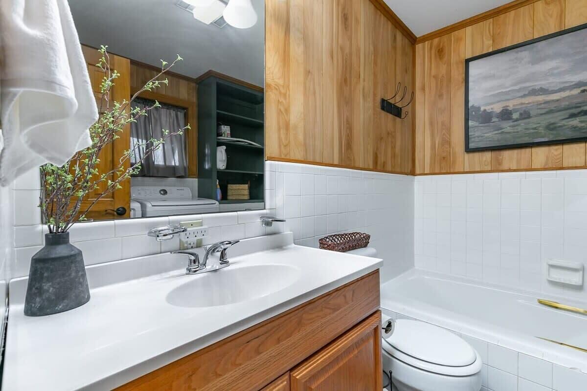 A modern bathroom with a white sink, wooden vanity, and a toilet.