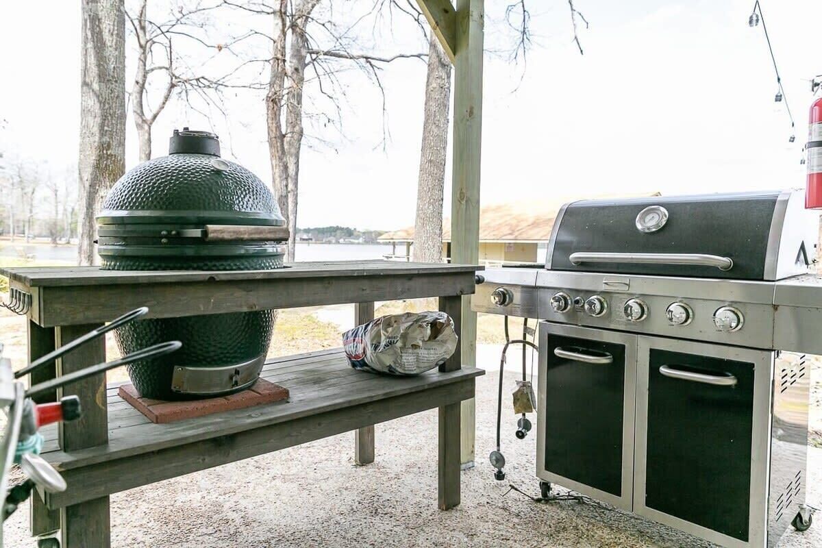 A portable grill setup with a built-in smoker and oven, placed on a wooden table outdoors.