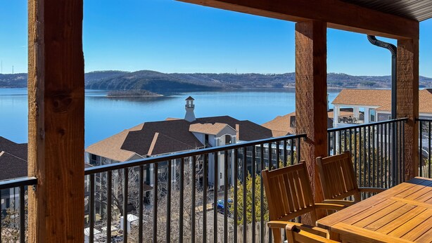 Une terrasse en bois offrant une vue sur un lac et des collines lointaines.