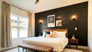 Une chambre à coucher avec un grand lit, un banc, une table de chevet et des lampes fixées au mur.