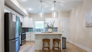 A modern kitchen with stainless steel appliances, a central island with stools, and pendant lighting.
