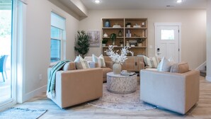 A living room with two beige sofas, a coffee table, and a bookshelf.